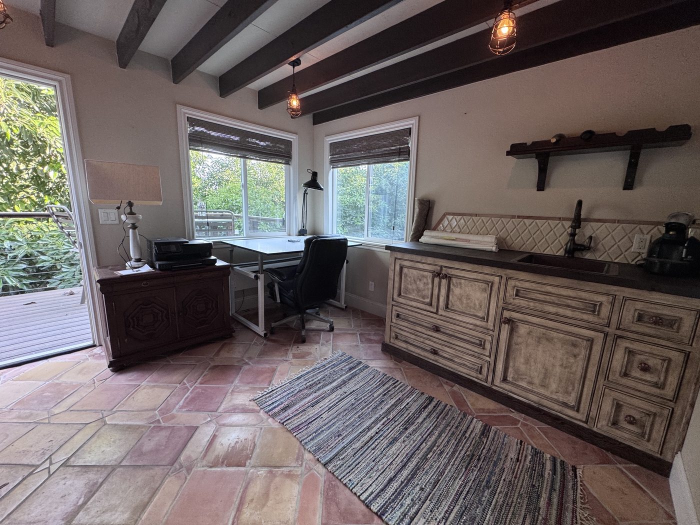 Barn studio interior with exposed beams, terracotta floors and prep sink