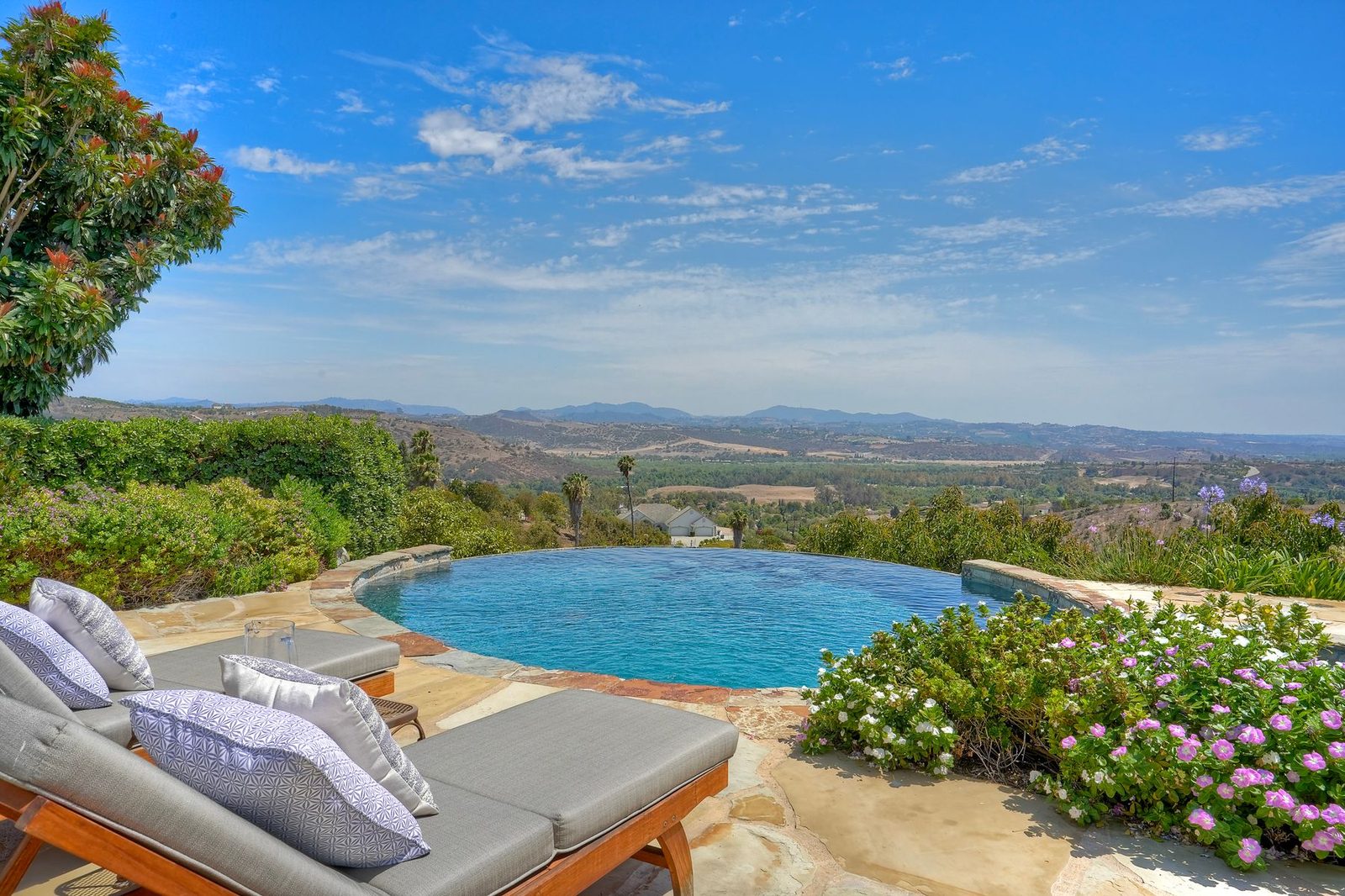 West-facing infinity-edge pool with views toward the coastline at 2484 Dos Lomas