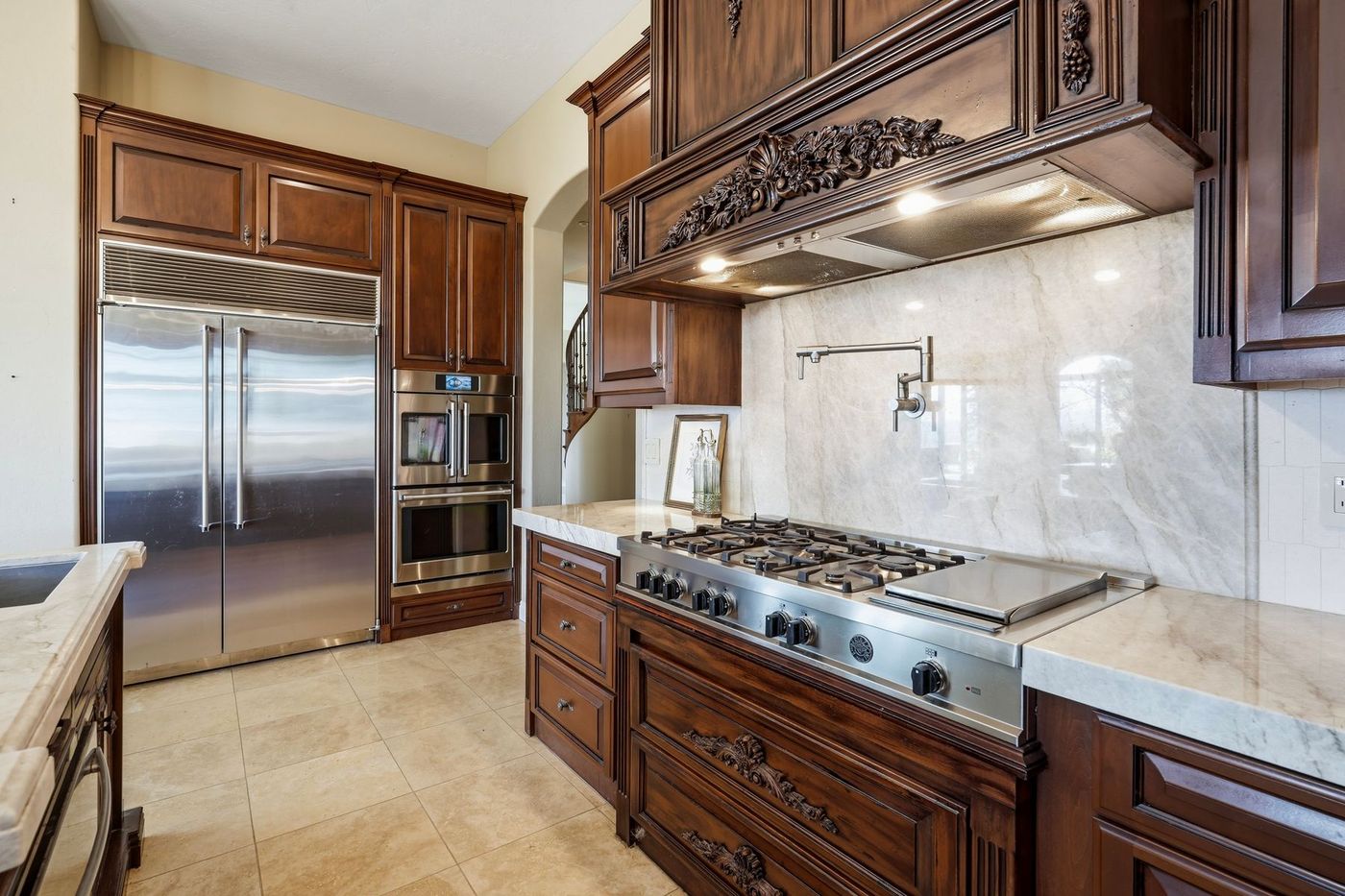 Bertazzoni professional range with griddle, pot filler, and marble slab backsplash