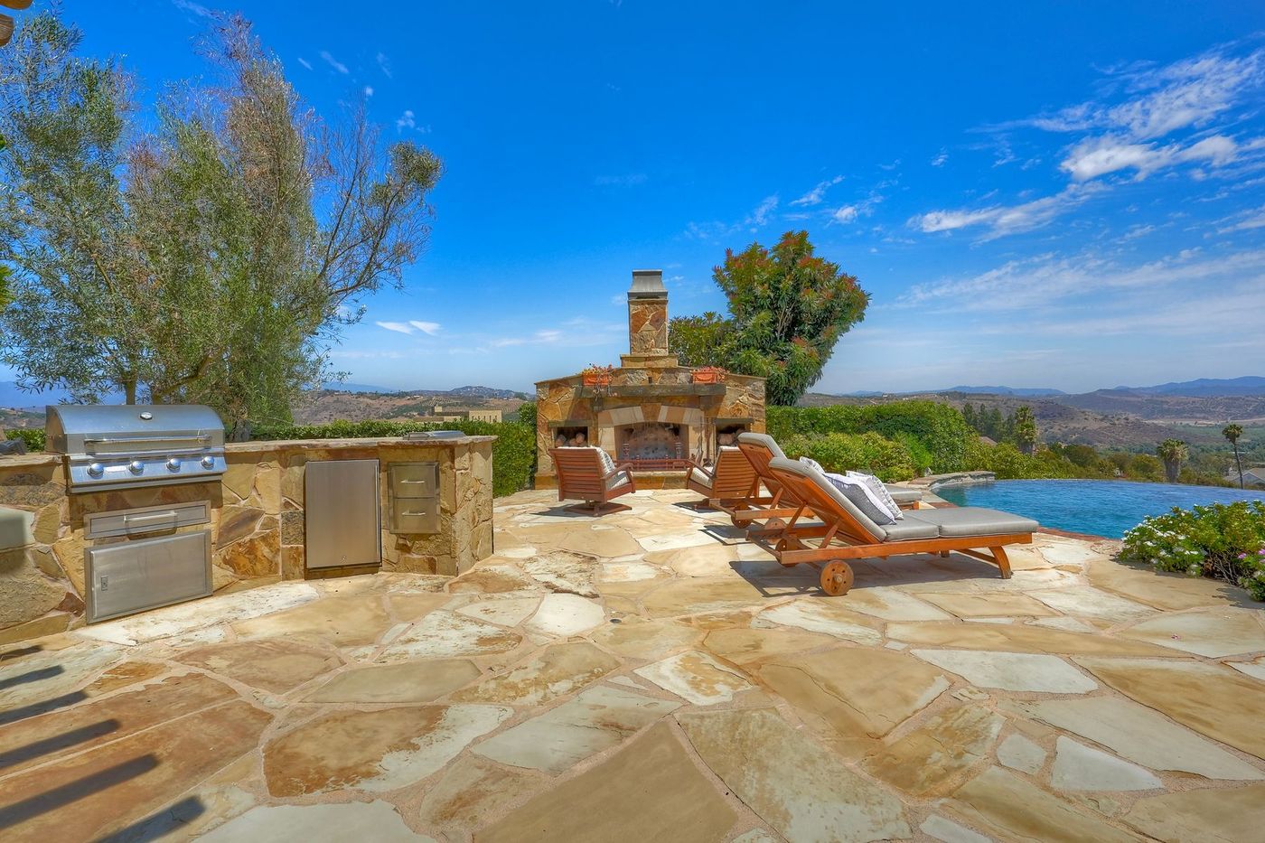 Poolside outdoor kitchen and wood-burning stone fireplace with valley views