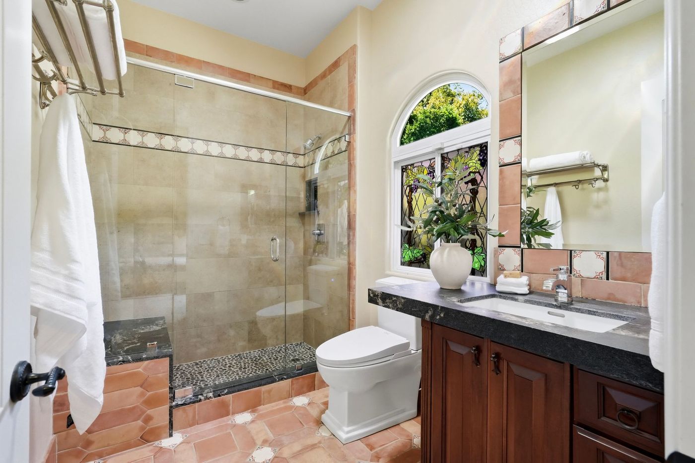 Spanish-tile guest bath with hand-painted inset and stained-glass window