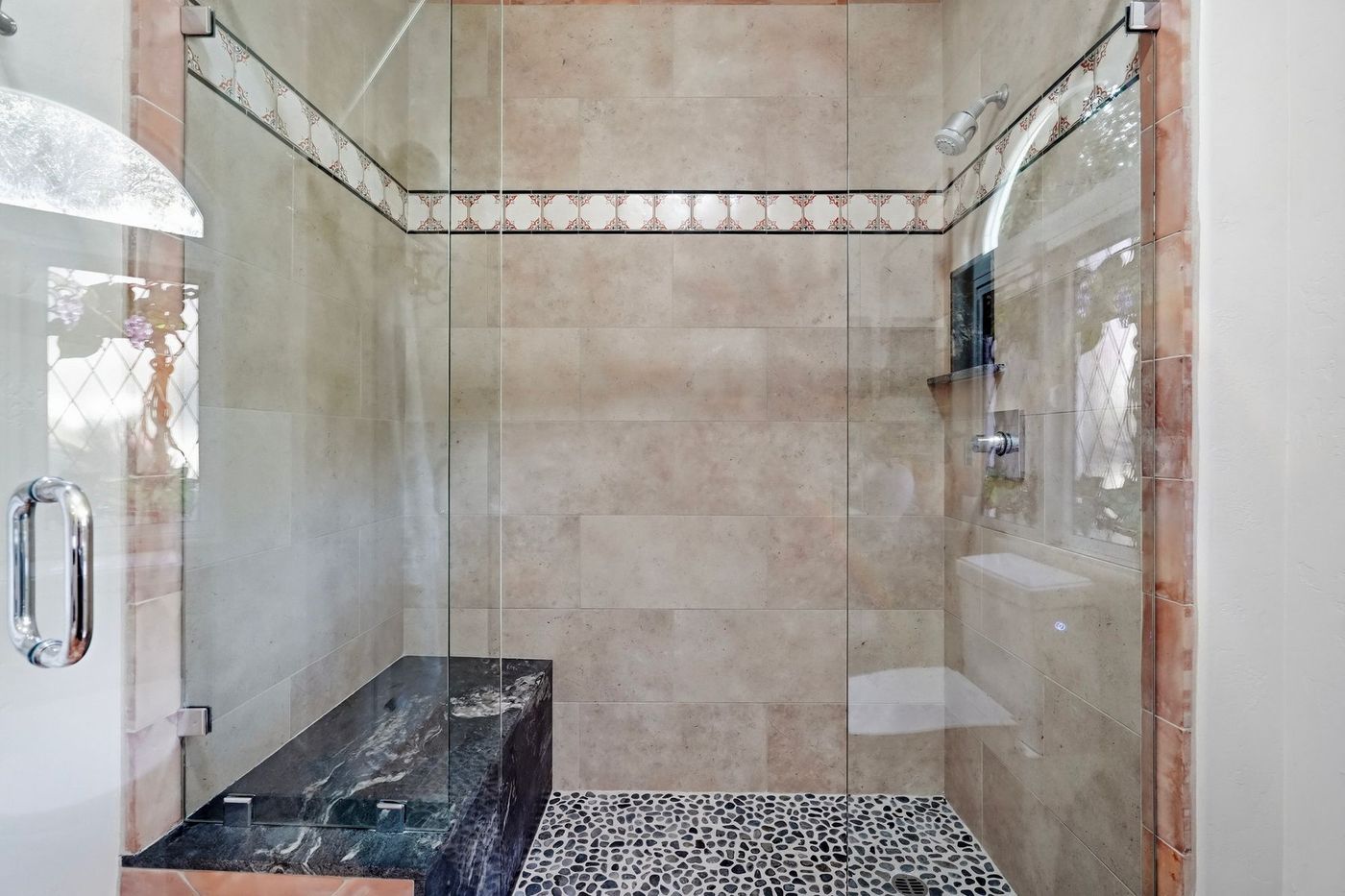 Frameless glass shower with pebble floor and stone bench